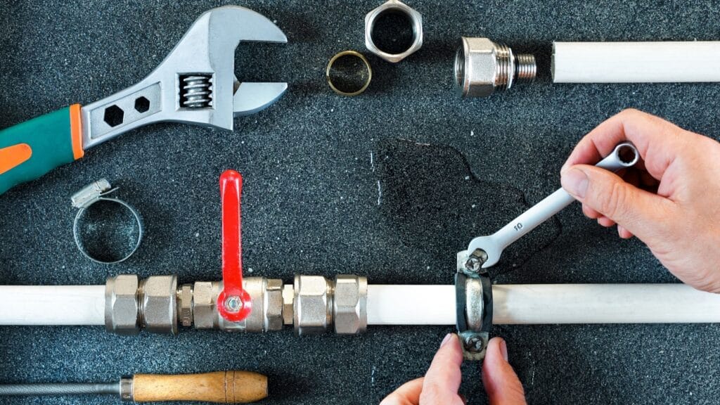 Plumber repairing a pipe valve with an adjustable wrench in Valrico