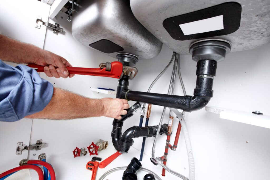 Plumber repairing drain pipes beneath a kitchen sink in Valrico